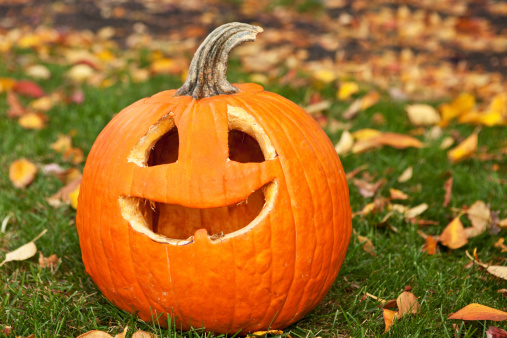 A carved pumpkin sitting on the grass.