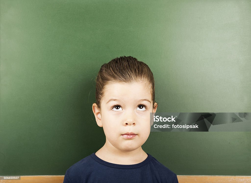 little student little girl thinking in front of empty blackboard in the classroom 4-5 Years Stock Photo