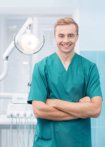 istock Happy dentist smiling at his dental office 506650761