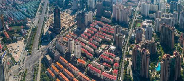 Aerial view over the roads and rooftops of a crowded residential area in Shanghai, China, traffic on the streets and highways, rows of apartment blocks and luxury condominium developments in the futuristic and fast growing Pudong district. ProPhoto RGB profile for maximum color fidelity and gamut.