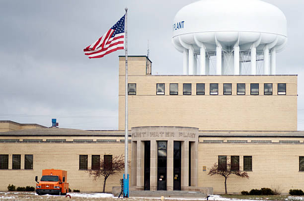 Flint Water Plant Tank Flint, Michigan, USA -  January 23, 2016: Flint Water Plant building with water tank in the background.  flint michigan stock pictures, royalty-free photos & images