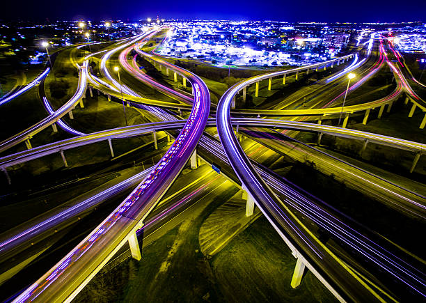 Aerial Austin Ambulance Interstate Interchange Expansive Night TimeLapse Aerial Ambulance Rushing Interstate Highway Interchange Night TimeLapse of Headlights and brake lights driving down the highway. The Crossover from 183 and Mopac Expressway. A long night shot in Austin Texas. Illuminated City lights. The Vast Expansive Never ending Fossil Fuel Using Energy Huge of A Civilization  light trail photos stock pictures, royalty-free photos & images