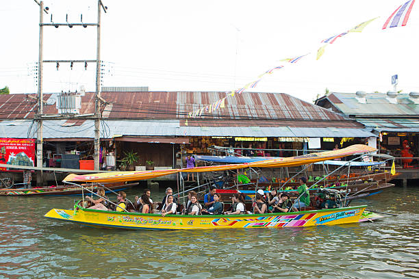 Foreigners are travelling on boat. Samut Songkhram, Thailand - January 23, 2016: Foreigners are travelling on boat at Amphora floating market on January 23, 2016 in Samut Songkhram, Thailand. mode of transport rowing rural scene retail stock pictures, royalty-free photos & images