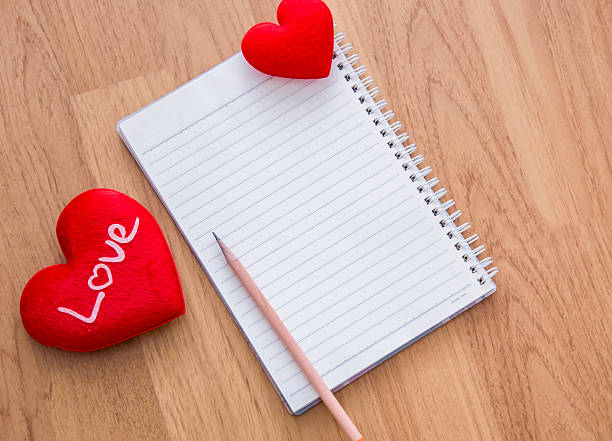istock pencil ,red heart, with note book on wooden table 506665582