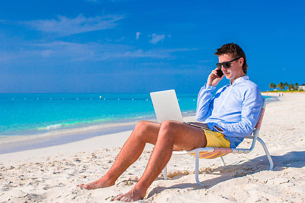 istock Young businessman using laptop on tropical beach 506665709