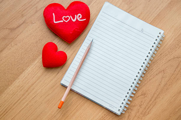 istock pencil ,red heart, with note book on wooden table 506665792