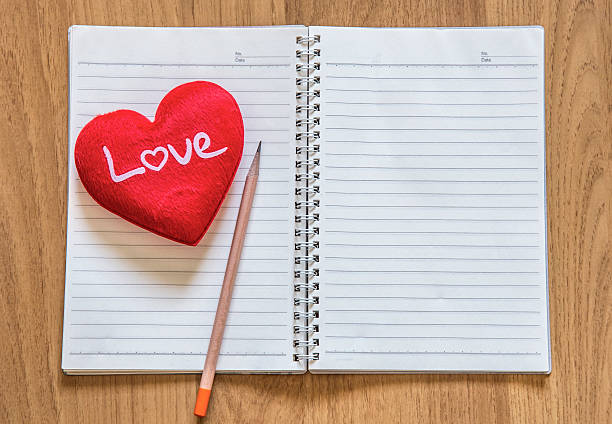istock pencil ,red heart, with note book on wooden table 506665902