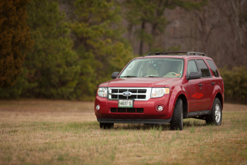 Williamsburg, Virginia, USA  - March 4, 2012: 2012 Red Ford Escape Sports Utility Vehicle parked on an empty field in the rural side of Virginia