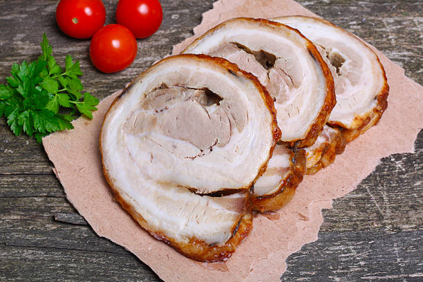 istock Sliced roasted roll pork loin with spices and fresh vegetables 506668224