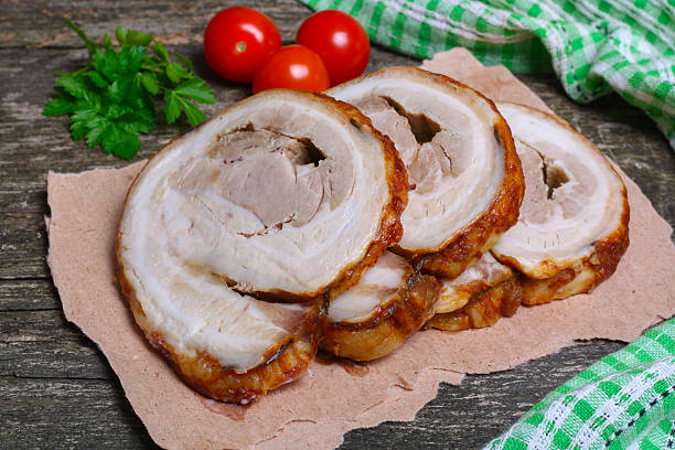 istock Sliced roasted roll pork loin with spices and fresh vegetables 506668612