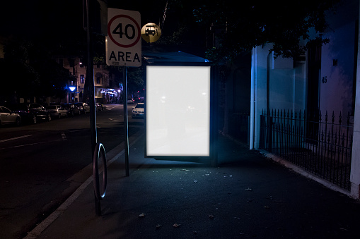 Bus stop billboard advert on city street at night