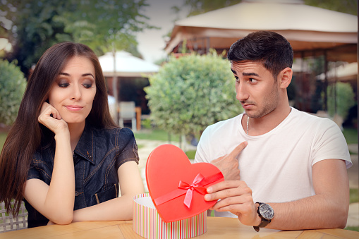 Unhappy girlfriend receiving bad gift from the man she loves