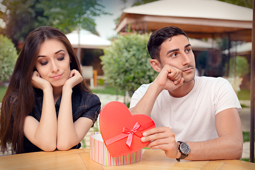 Unhappy girlfriend receiving bad gift from the man she loves
