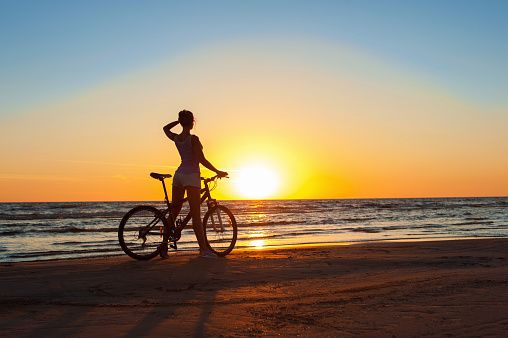 Moment in time. Sporty woman cyclist silhouette at sunset