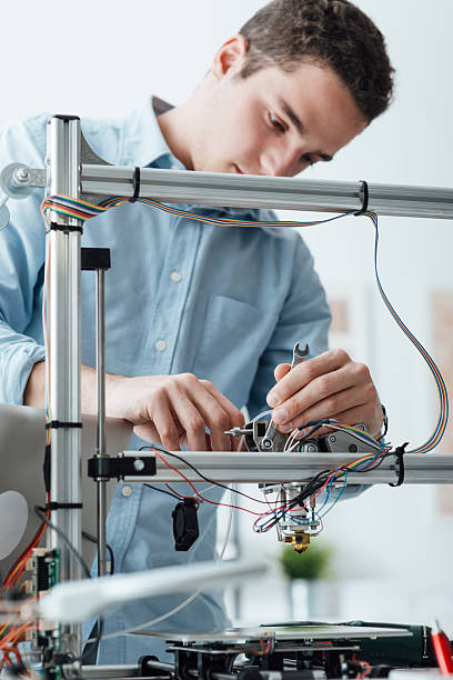 Engineer working on a 3D printer Young efficient engineer working on a 3D printer and adjusting components prototype photos stock pictures, royalty-free photos & images