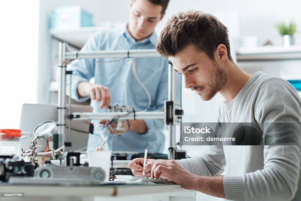 Engineering students working in the lab Engineering students working in the lab, a student is using a 3D printer in the background Engineer Stock Photo