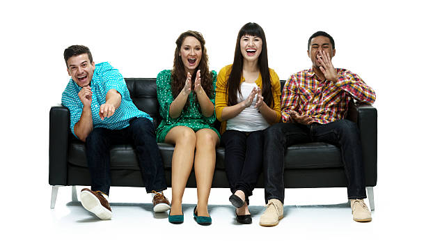 istock Cheerful friends sitting on sofa laughing & clapping 506688509