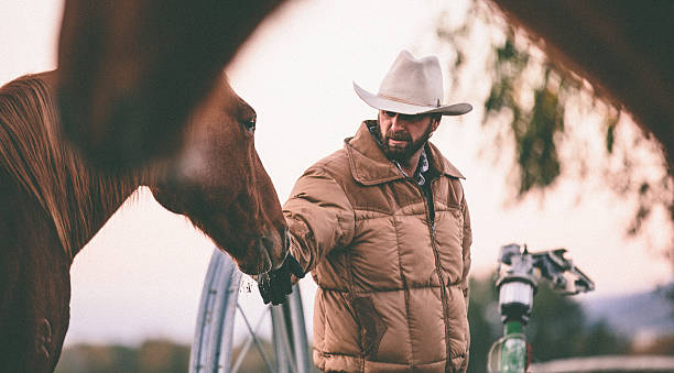 istock Rancher pets horse on nose while working in field 506690405