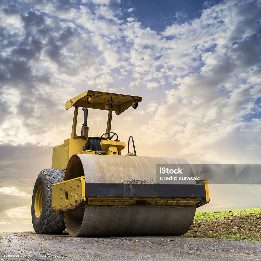 Road roller at construction site Road roller at road construction site with cloudy blue sky during sunset Steamroller Stock Photo