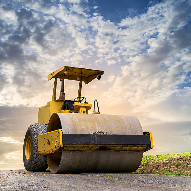 Road roller at construction site Road roller at road construction site with cloudy blue sky during sunset compactor photos stock pictures, royalty-free photos & images