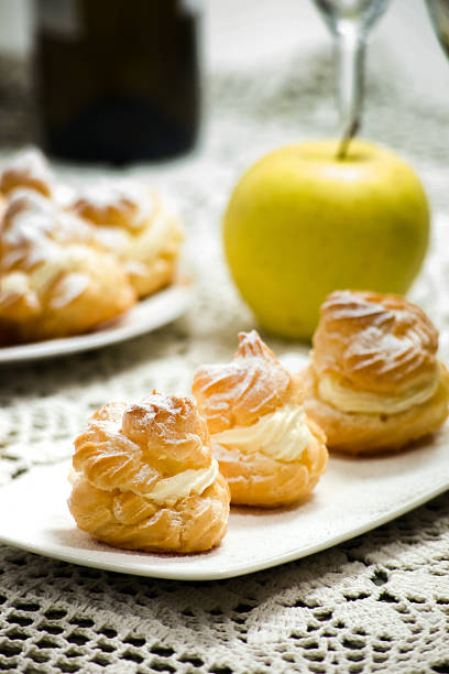 Close up of a cream puff on a white plate, table setting. Selective focus