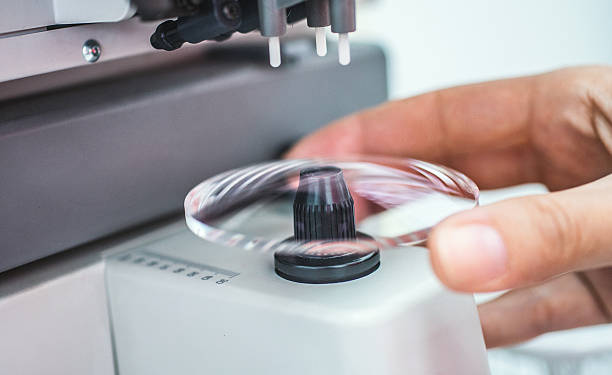 Making eyeglasses lens. Closeup of unrecognizable caucasian technician's hand placing piece of lens glass into machine that will mark the focal center before sending it to glass grinder. concave stock pictures, royalty-free photos & images