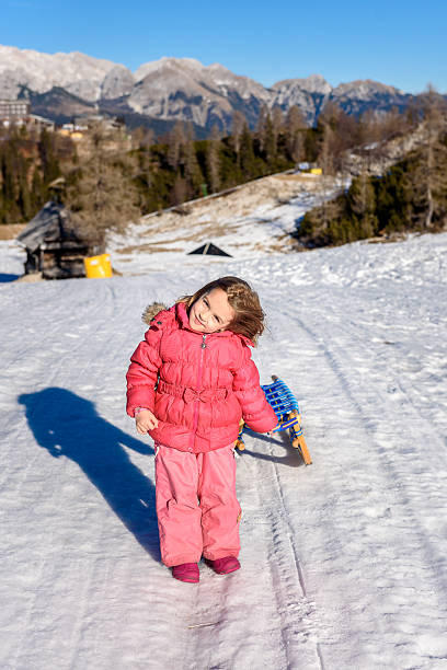 istock Girl pulling snow sledge in ski resort  wearing winter clothes 506703542