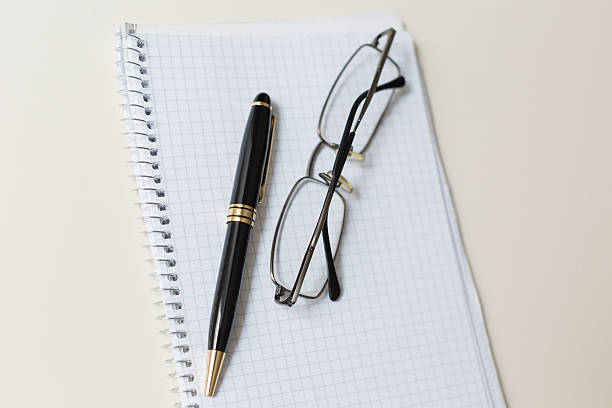 istock black pen and glasses with white pad or notepad 506705524
