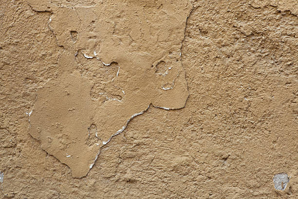 istock Old ochre painted stucco wall with cracked plaster. Background t 506706740