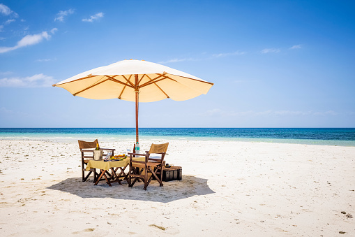 Beach umbrella and picnic table and chairs on a secluded sandbar in the Indian Ocean in Zanzibar (Africa).
