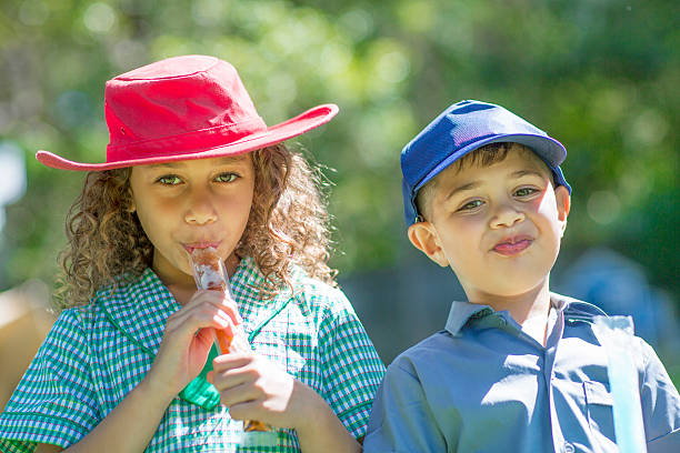 Three kids are playing music together. Kids are playing flutes in music class on a sunny day.\n