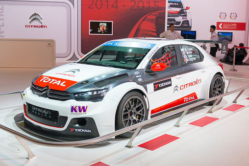 Brussels, Belgium - Januari 12, 2016: Citroen C Elysee WTCC race car. Citroën participated in the 2015 FIA World Touring Championship and won the overall championship with José María López, and the next three places for Yvan Muller, Sébastien Loeb and Ma Qing Hua. The car is on display during the 2016 Brussels Motor Show. The car is displayed on a motor show stand, with lights reflecting off of the body. There are people looking around in the background.