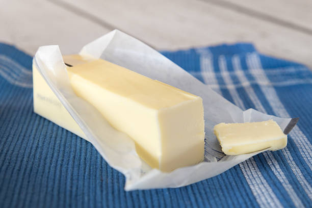 Butter Stick of unwrapped butter on blue cloth butter stock pictures, royalty-free photos & images