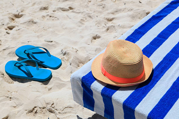 istock Straw hat, towel and flip flops on a tropical beach 506715233