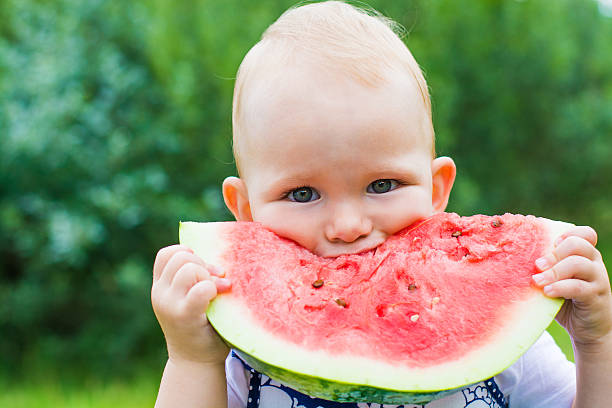 rapariga engraçada comer melancia na grama no verão - watermelon summer melon portion imagens e fotografias de stock
