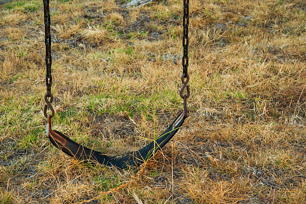 Empty Swing on Collapsing Swingset in an Abandoned Playground stock photo