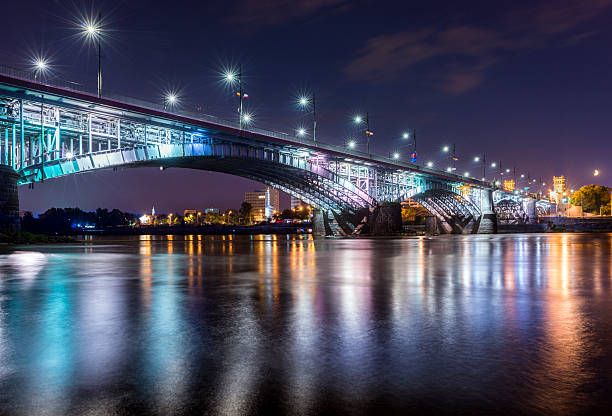 istock Backlit bridge at night and reflected in the water. 506730245