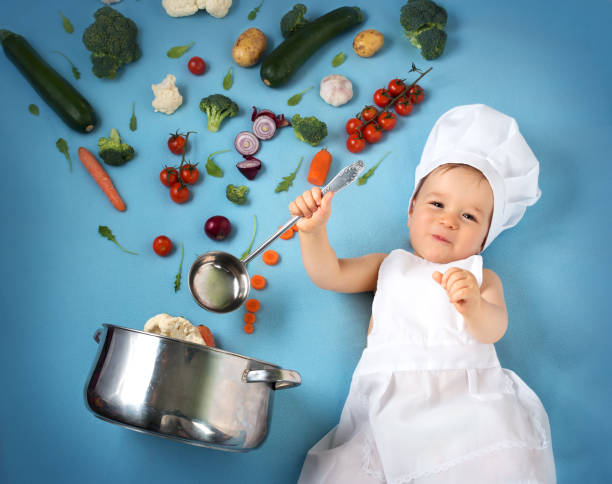istock Baby boy in chef hat with cooking pan and vegetables 506755402