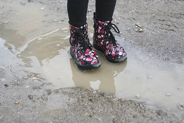 istock Legs of child in rain boots standing in puddle. 506757502