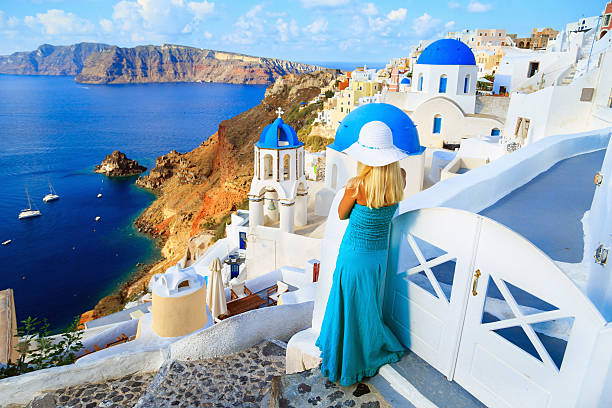 blond kobieta na ulicy w santorini patrząc na morze - hat oia europe vacations zdjęcia i obrazy z banku zdjęć