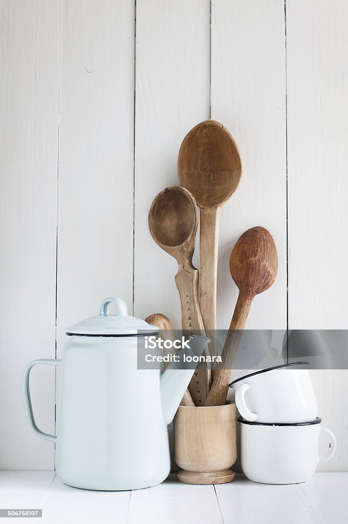 coffee pot, enamel mugs and rustic spoons Home kitchen still life: Vintage coffee pot, enamel mugs and antique rustic wooden spoons on a barn wall background, soft pastel colors. Arrangement Stock Photo