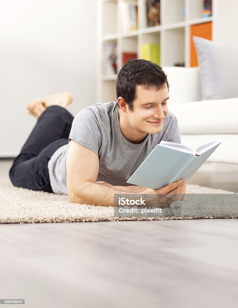 Young man at home Young man lying down with book and smiling 30-39 Years Stock Photo