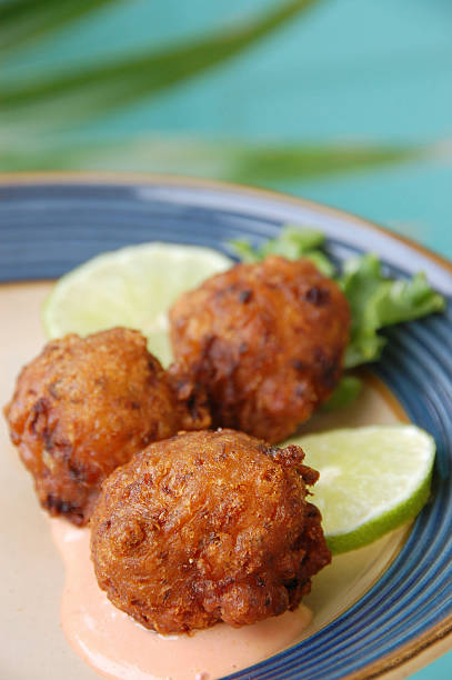Florida Keys Conch Fritters Three deep fried conch fritters, a specialty of the Florida Keys, served with lime and dipping sauce. conch shell photos stock pictures, royalty-free photos & images
