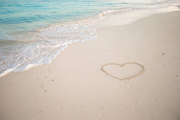 istock Heart painted in white sand on a tropical beach 506760565