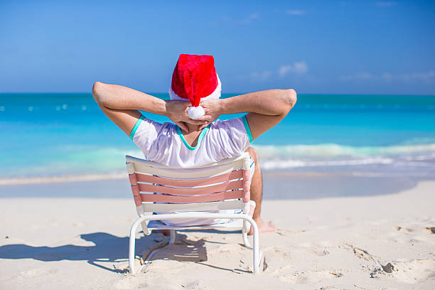 istock Young man in santa hat relax at beach 506761117
