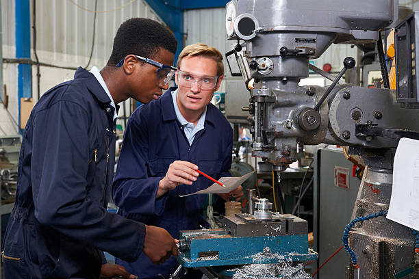 istock Engineer Showing Apprentice How to Use Drill In Factory 506762565