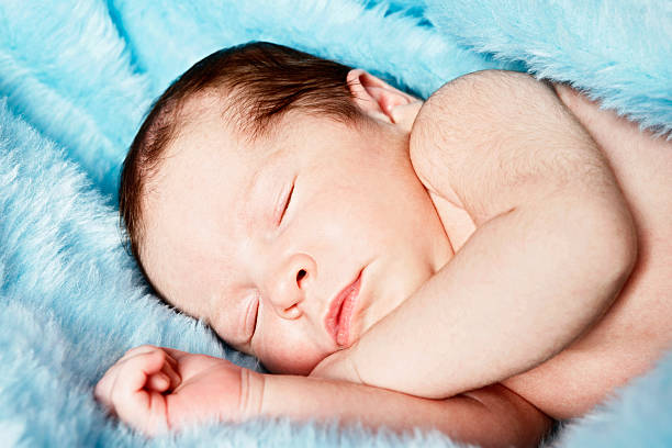 little cherub! neugeborenes baby schlafen auf blaue decke - fake fur white happiness beginnings stock-fotos und bilder