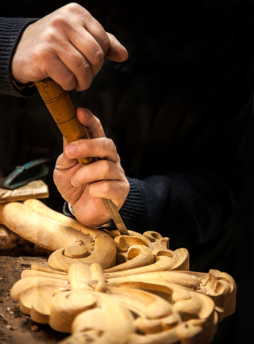 An engraver is carving a wood frame