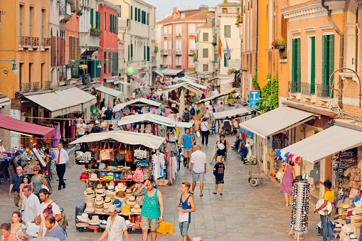 Venice, Italy - July 17, 2015: Locals and tourists walking trough a street full of souvenir shops and cafes 