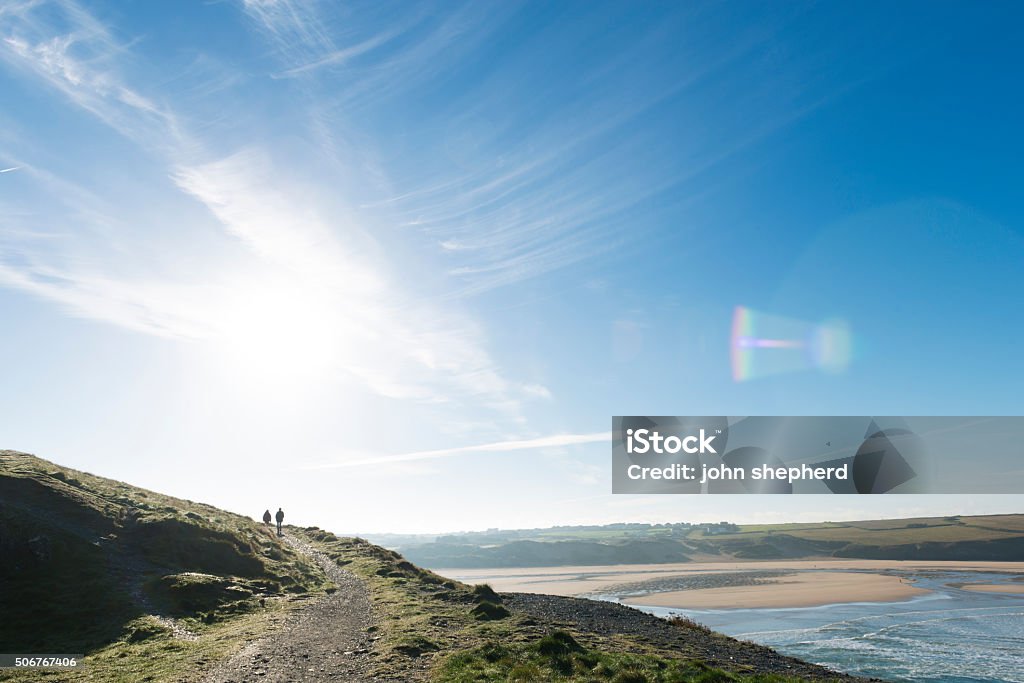 Views over Crantock Beach, Newquay, Cornwall in Autumn Sunshine Two unrecognisable people walking along the coast path in Pentire, Newquay, Cornwall on a bright sunny Autumn day. Views over Crantock beach. Coastline Stock Photo